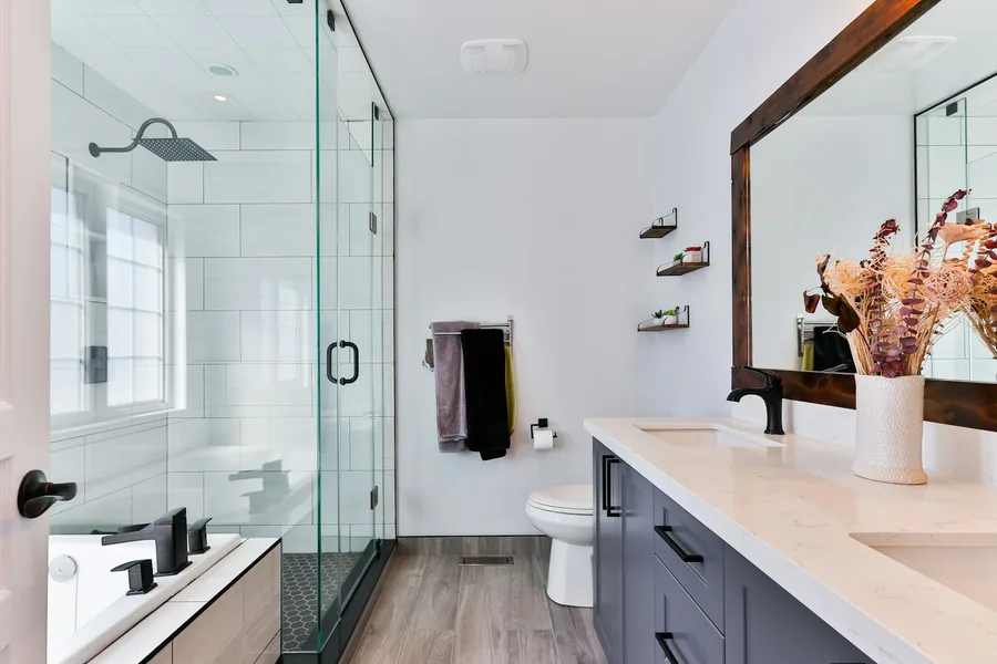 Bathroom with glass shower enclosure, blue vanity and timber-framed mirror